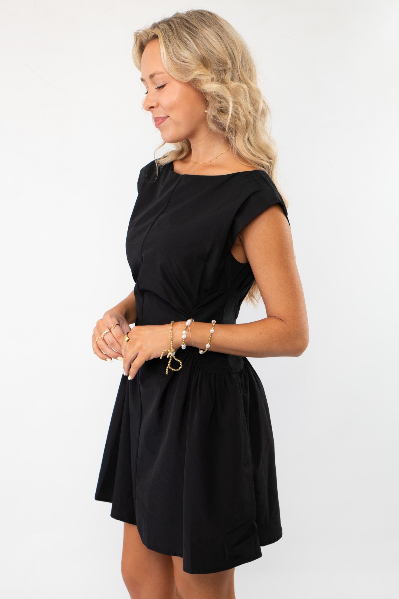 Side profile of the With Love Black Ruched Waist Mini Dress highlighting its structured fit and feminine silhouette. Ideal for graduations or evening outings.