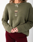 Close-up of the Martini A Day Olive Beaded Sweater showcasing detailed espresso martini beadwork on soft olive knit fabric. Ideal for trendy winter wear.