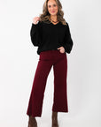 Women's Olivia Oversized Black V‑Neck Sweater paired with wide-leg burgundy trousers and brown boots, ideal for casual or dressy wear.