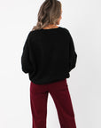 Back view of Olivia Oversized Black V‑Neck Sweater highlighting its draped silhouette and cozy knit fabric, perfect for layering year-round.