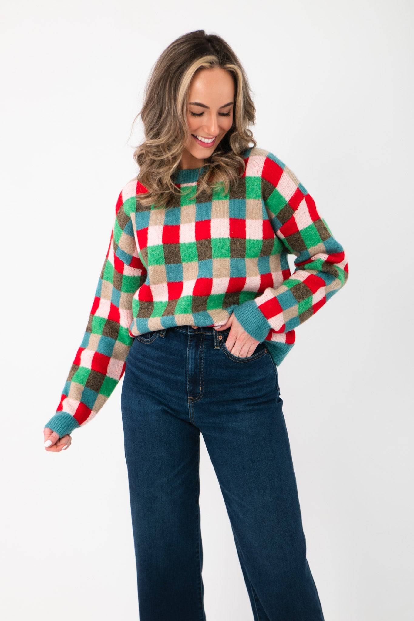 Festive Holiday Check Knit Sweater in blue, red, and green check pattern paired with dark denim jeans, perfect for winter celebrations.
