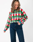 Festive Holiday Check Knit Sweater in blue, red, and green check pattern paired with dark denim jeans, perfect for winter celebrations.