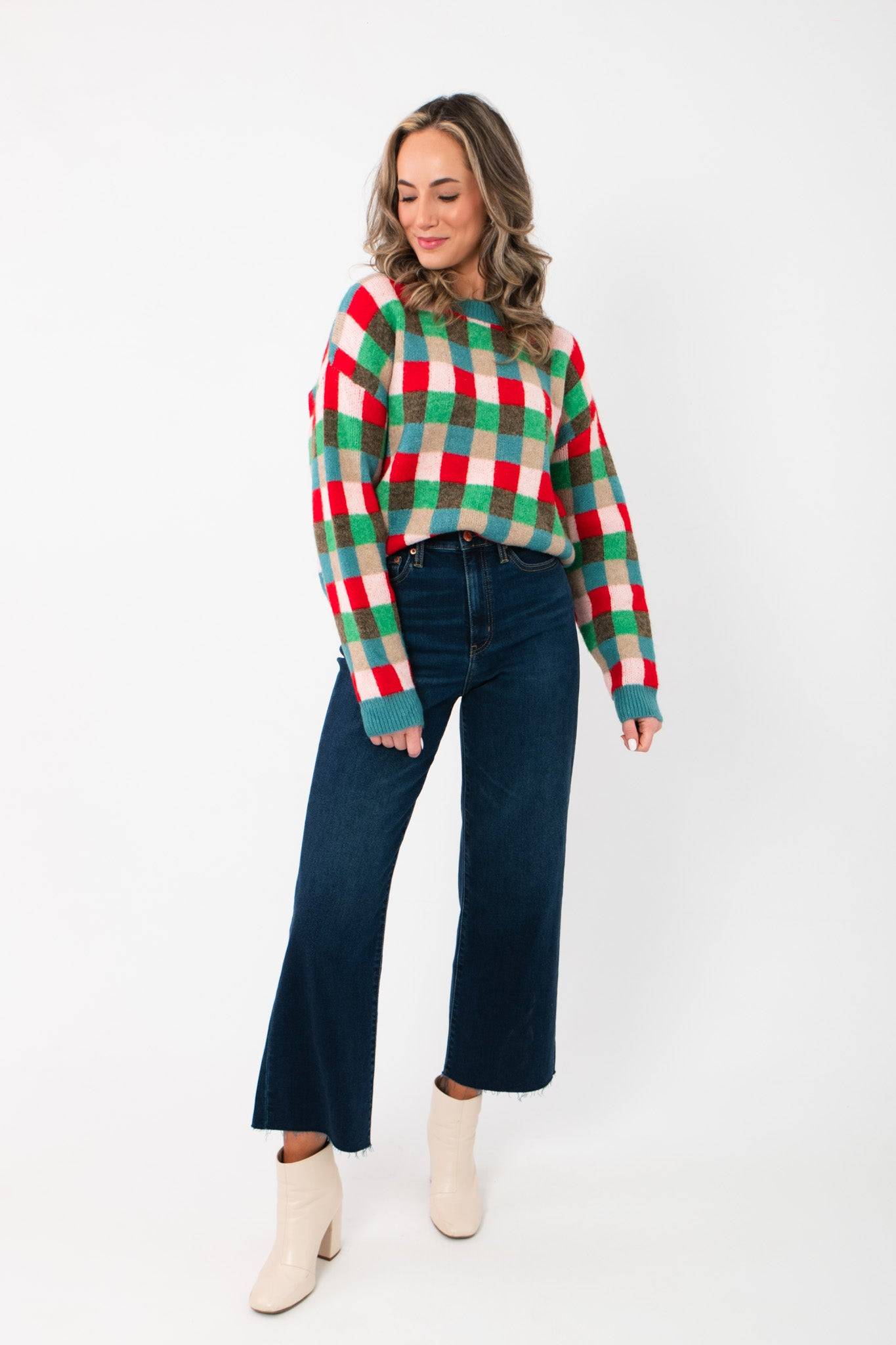 Holiday Check Knit Sweater styled with wide-leg dark jeans and ivory boots, showcasing its colorful festive pattern and cozy fit.