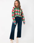 Holiday Check Knit Sweater styled with wide-leg dark jeans and ivory boots, showcasing its colorful festive pattern and cozy fit.