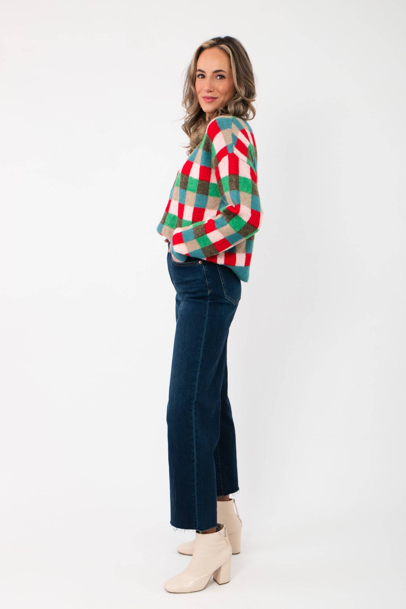 Side view of Holiday Check Knit Sweater in red, green, and blue checks, paired with denim for a casual holiday look.
