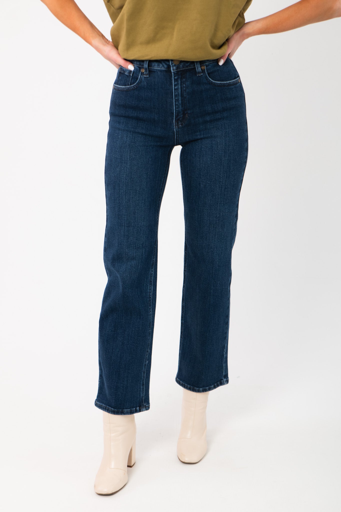 Bennett Dark Denim Straight Leg Jean with high waist and dark wash, styled with cream ankle boots for a winter-ready look.