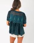 Back view of Lacy Teal Velvet Babydoll Top showing sheer mesh panel and lace detailing, paired with cream shorts for a chic outfit.