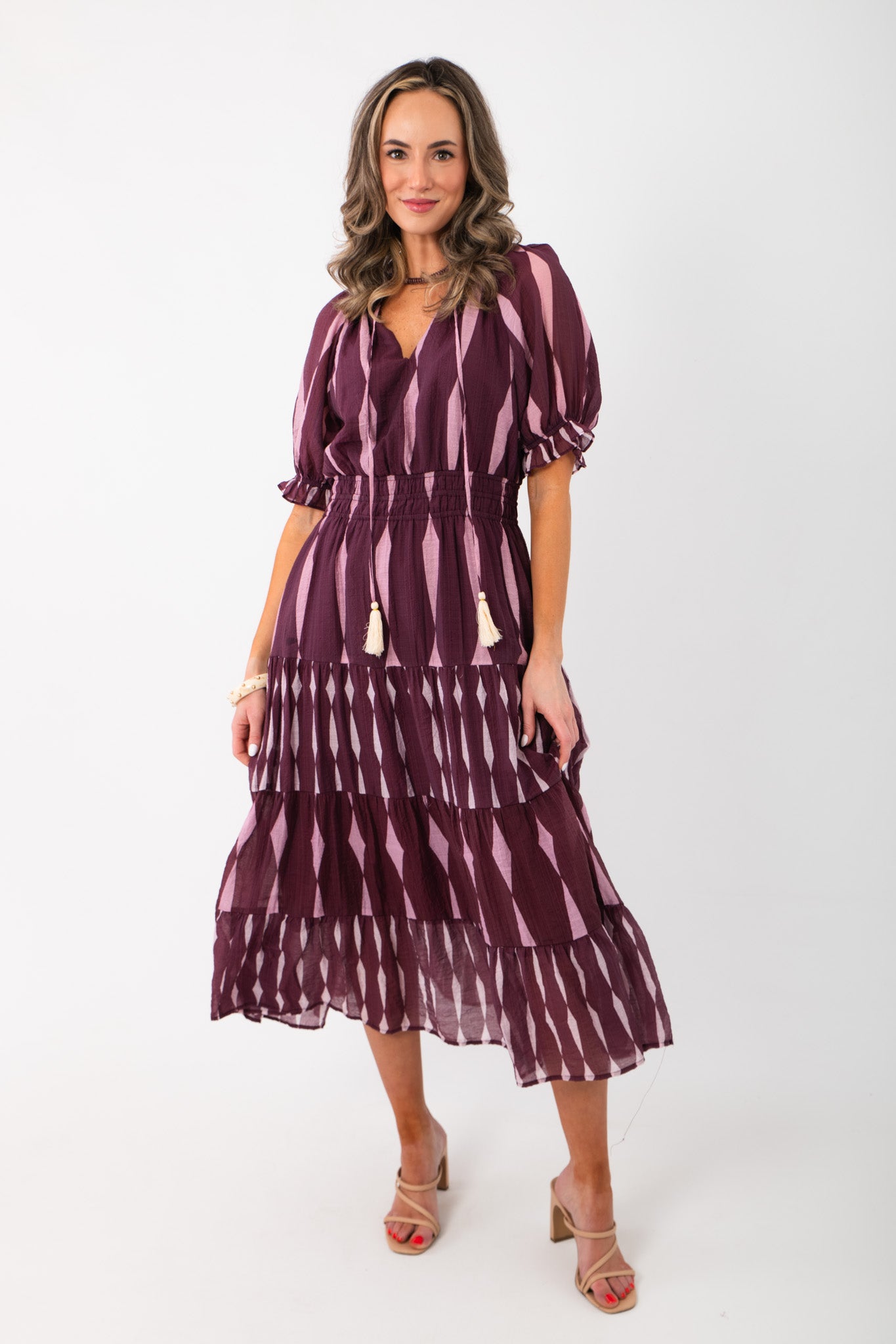 THML Burgundy & Pink Pattern Maxi Dress with v-neck ties, puff sleeves, and tiered skirt, styled for a chic holiday or Valentine's look.