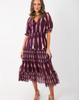 THML Burgundy & Pink Pattern Maxi Dress with v-neck ties, puff sleeves, and tiered skirt, styled for a chic holiday or Valentine's look.