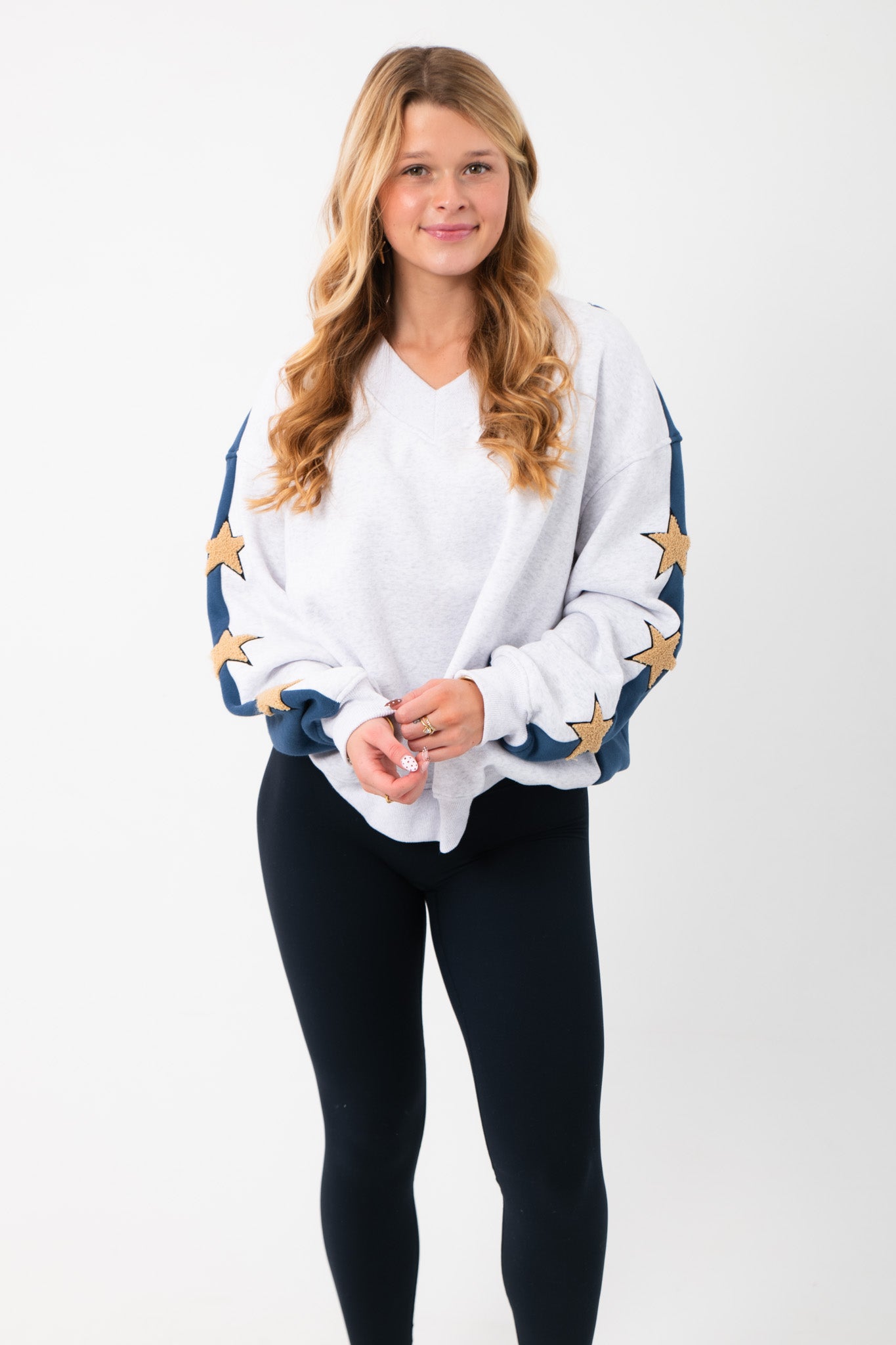 Wrapped in Stars Grey & Navy Star Sweatshirt with gold star accents on sleeves, styled with black leggings. Cozy top from L. Mae Boutique.