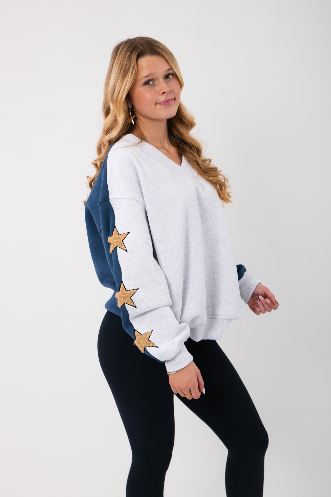 Side view of the Wrapped in Stars Sweatshirt showing navy sleeves with gold star patches, combining comfort and celestial style.