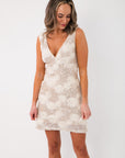 Front view of Champagne Rose Sequin Mini Dress featuring a deep V-neckline, white rose detailing, and shimmering sequins for festive elegance.