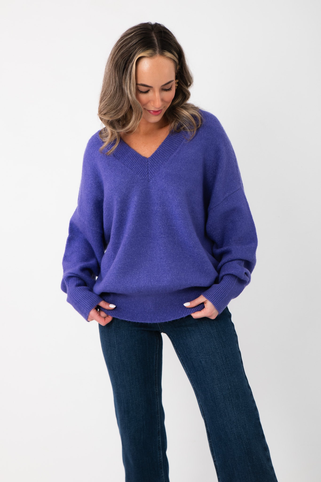 Olivia Oversized Purple V‑Neck Sweater with relaxed fit and ribbed cuffs, styled with dark denim jeans for a cozy fall look.