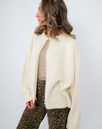 Laura Ivory Pearl Cardigan – Soft ivory cardigan featuring pearl trim and relaxed fit, ideal for layering over neutral tones.