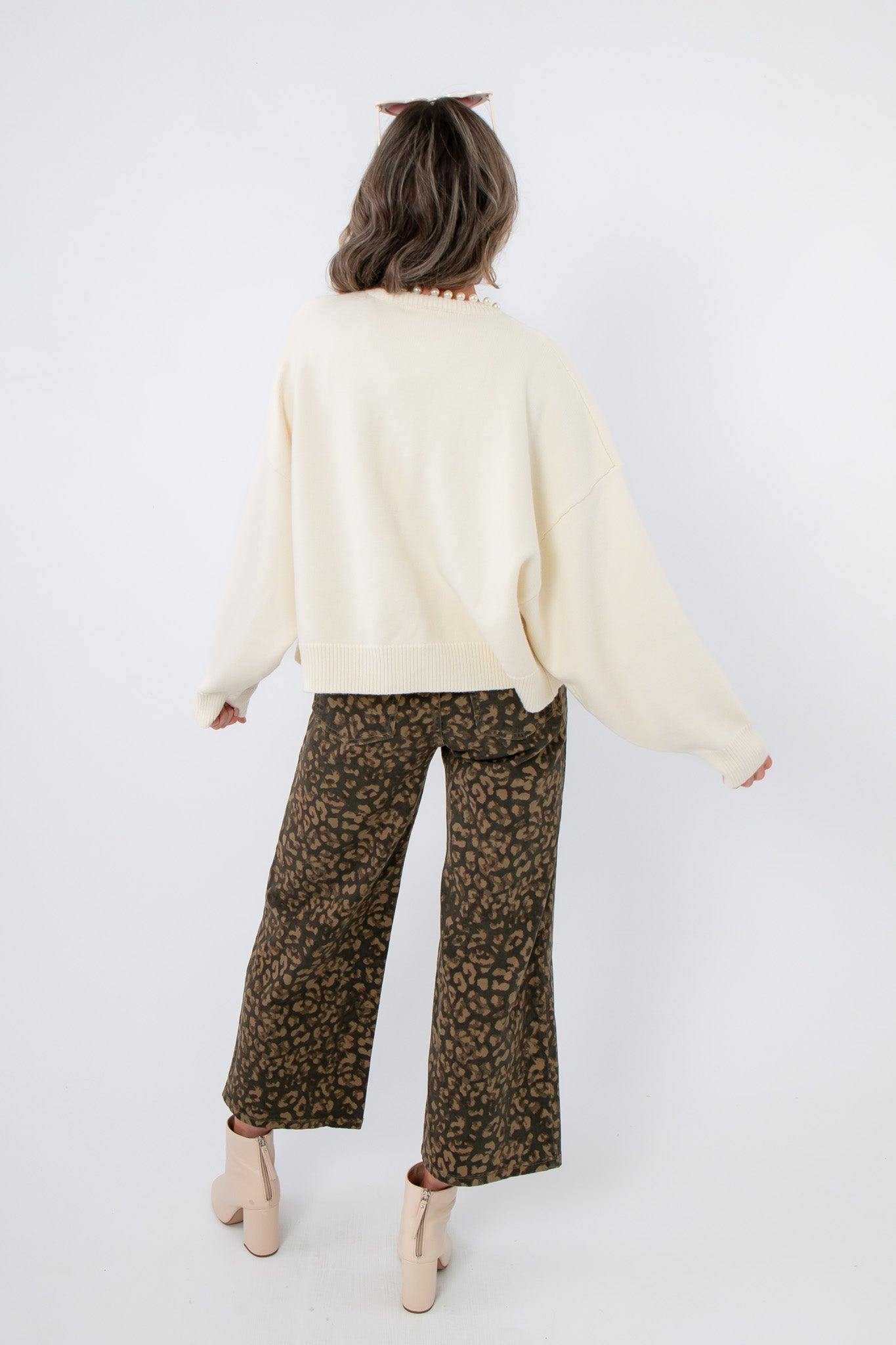 Laura Ivory Pearl Cardigan – Back view of elegant ivory cardigan with ribbed hem and dropped shoulders, styled for casual chic.