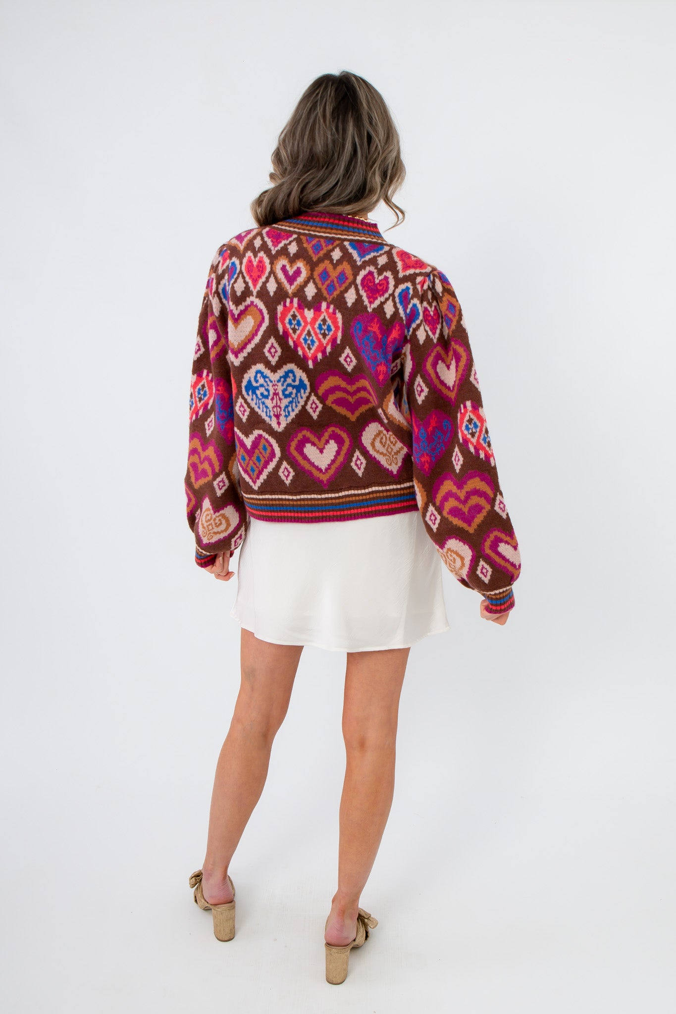 Back view of Chocolate Hearts Patterned Sweater showcasing detailed heart and diamond patterns in pink, red, and blue on a warm brown knit.