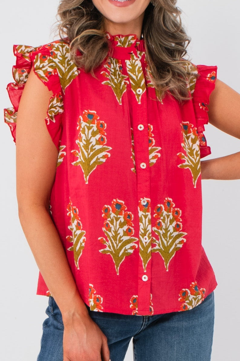 Woman wearing a THML red floral blouse with ruffled sleeves on a white background