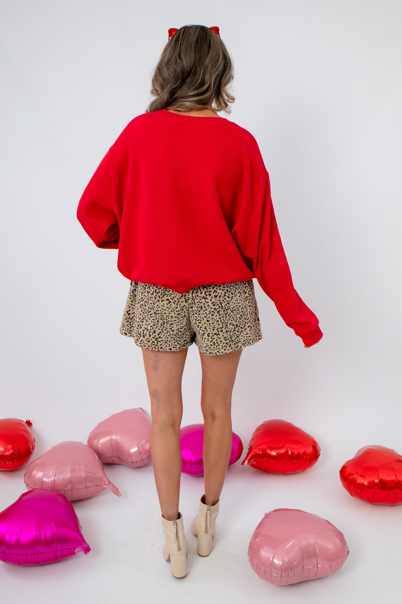 Back view of Lover Red Ribbed Sweater – Cozy Valentine’s Day Pullover showing ribbed texture and loose fit, styled with leopard shorts.