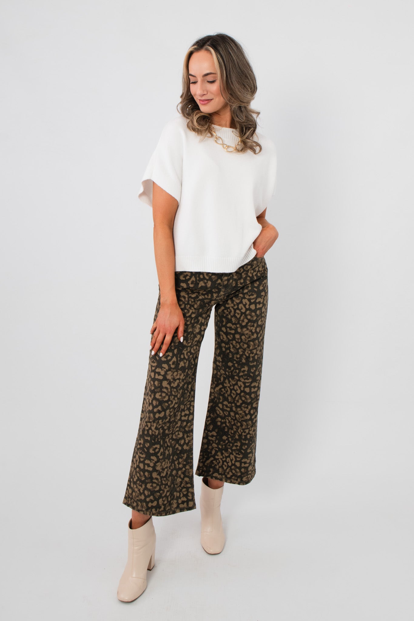 Model wearing Whatever The Weather Ivory Sleeveless Sweater – Oversized Spring Knit paired with wide-leg leopard pants and ankle boots.