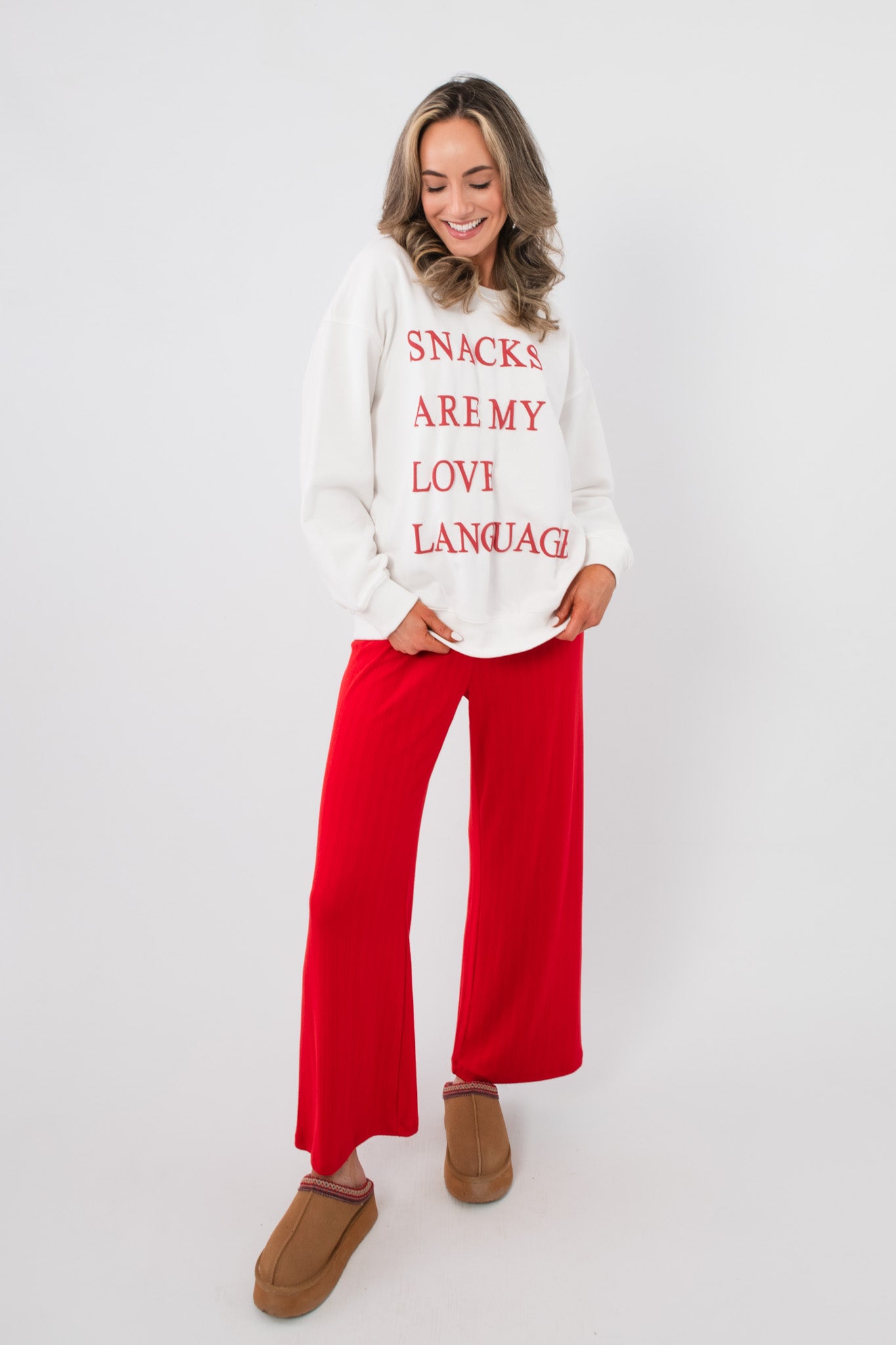 White Snacks Are My Love Language Sweatshirt with bold red lettering, paired with red lounge pants and tan slippers for a comfy outfit.