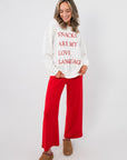 White Snacks Are My Love Language Sweatshirt with bold red lettering, paired with red lounge pants and tan slippers for a comfy outfit.