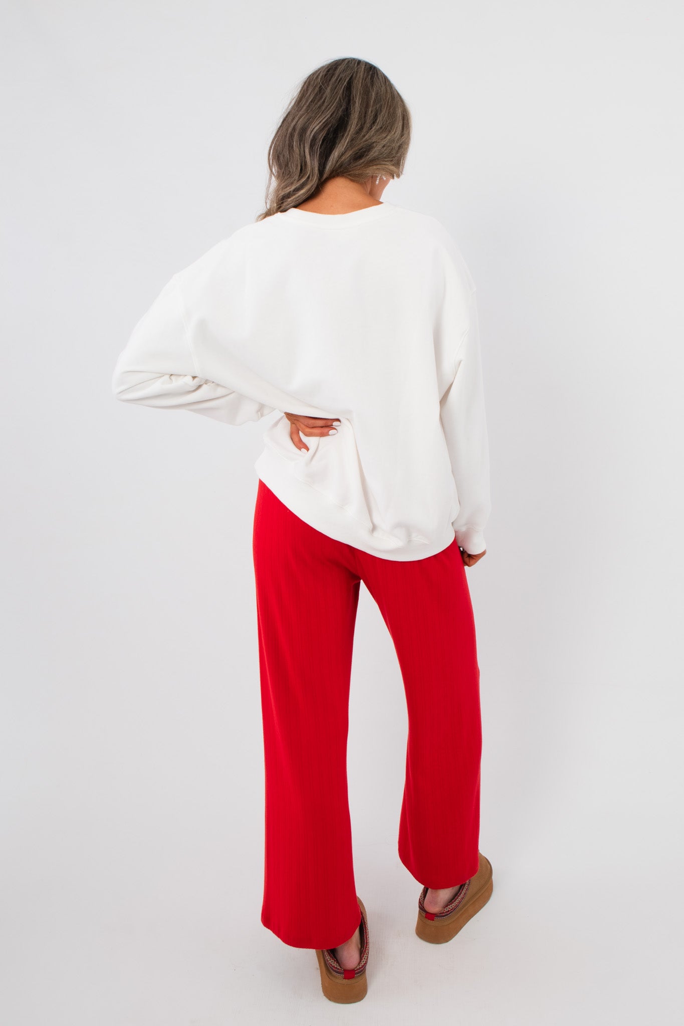 Back view of the Snacks Are My Love Language Sweatshirt – plain white pullover paired with red pants, highlighting relaxed fit.