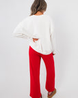 Back view of the Snacks Are My Love Language Sweatshirt – plain white pullover paired with red pants, highlighting relaxed fit.