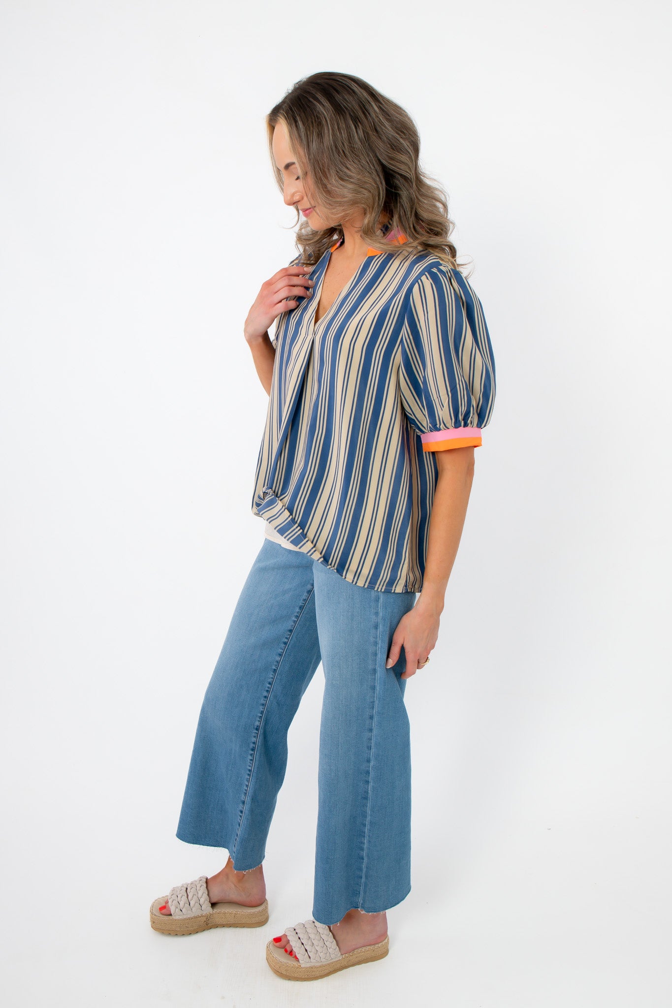Side view of THML Blue Poppy Striped V-Neck Top showing relaxed fit and colorful sleeve accents, paired with cropped denim pants.