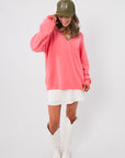 Cozy oversized Show Me Your Mumu Coral Knit Anything Goes Sweater paired with white skirt and boots, perfect for layering in spring.
