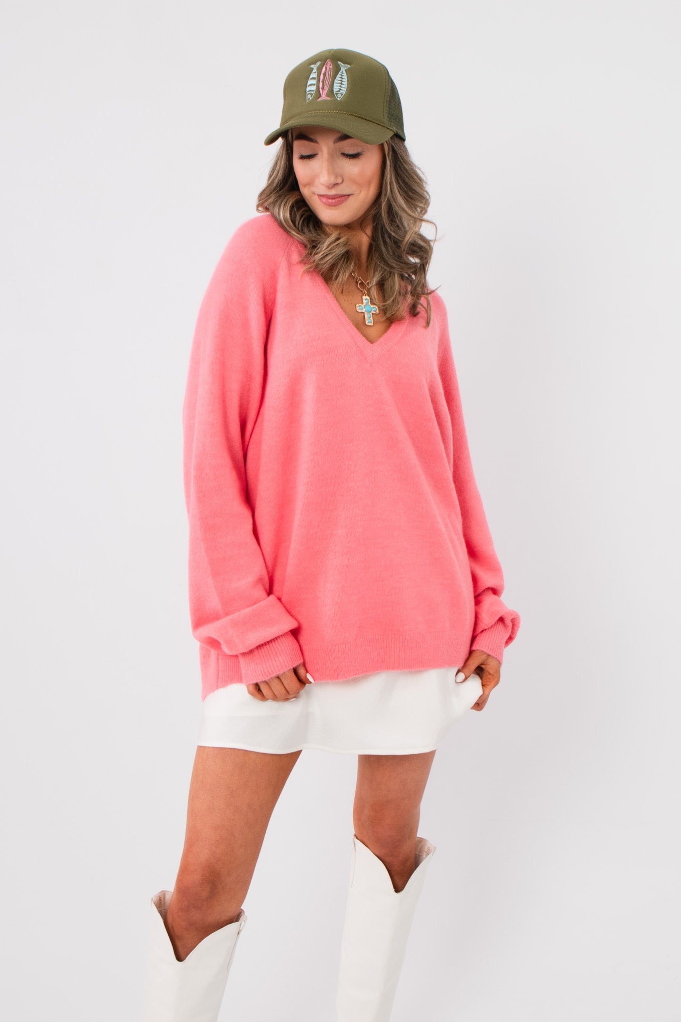 Show Me Your Mumu Coral Knit Anything Goes Sweater with oversized fit and v-neck, styled with white mini skirt and white boots.