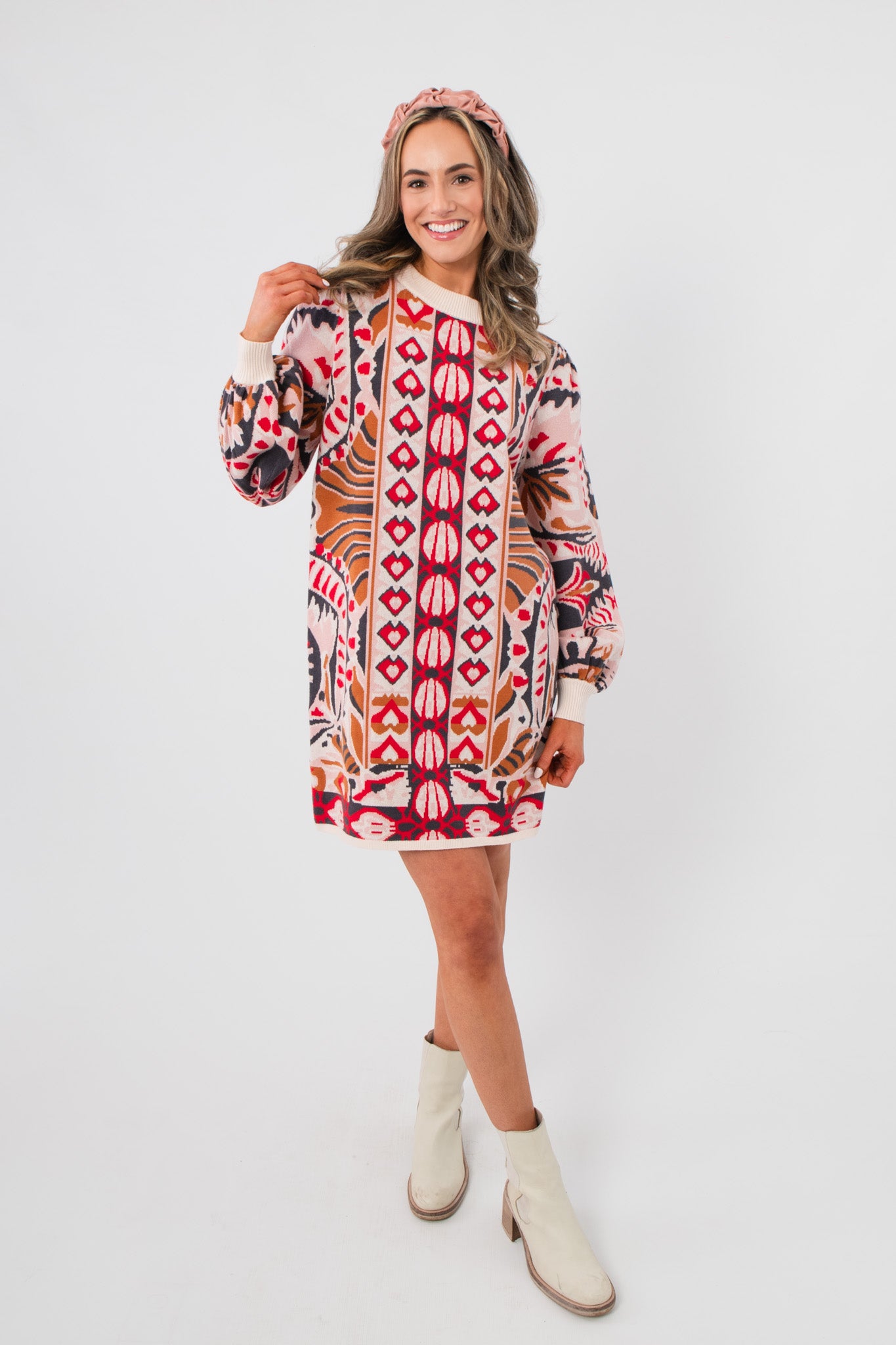 Cathy Pink Jacquard Knit Mini Dress with bold geometric patterns, balloon sleeves, and crew neck, styled with boots for a chic layered look.
