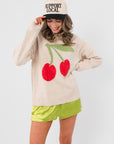 Key Lime Green Silky Shorts styled with a cherry print sweater and 'Support Local' cap, showcasing a playful summer outfit.