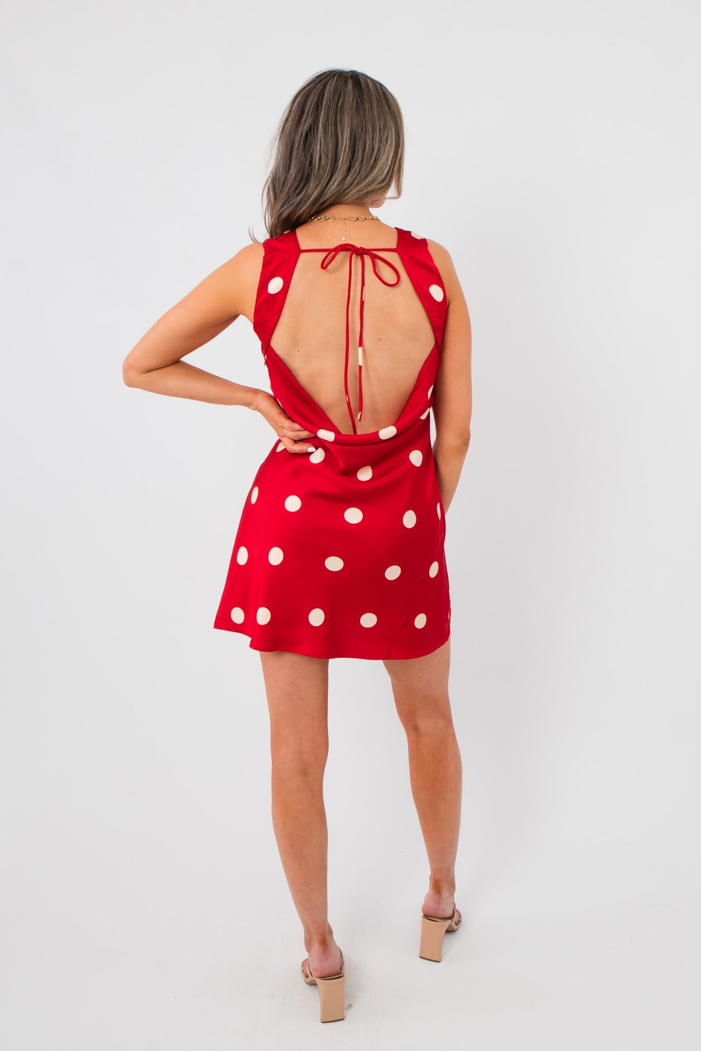 Back view of Cherry Cola Polka Dot Mini Dress with open back and tie closure, combining elegance and fun for stylish summer or bachelorette outfits.