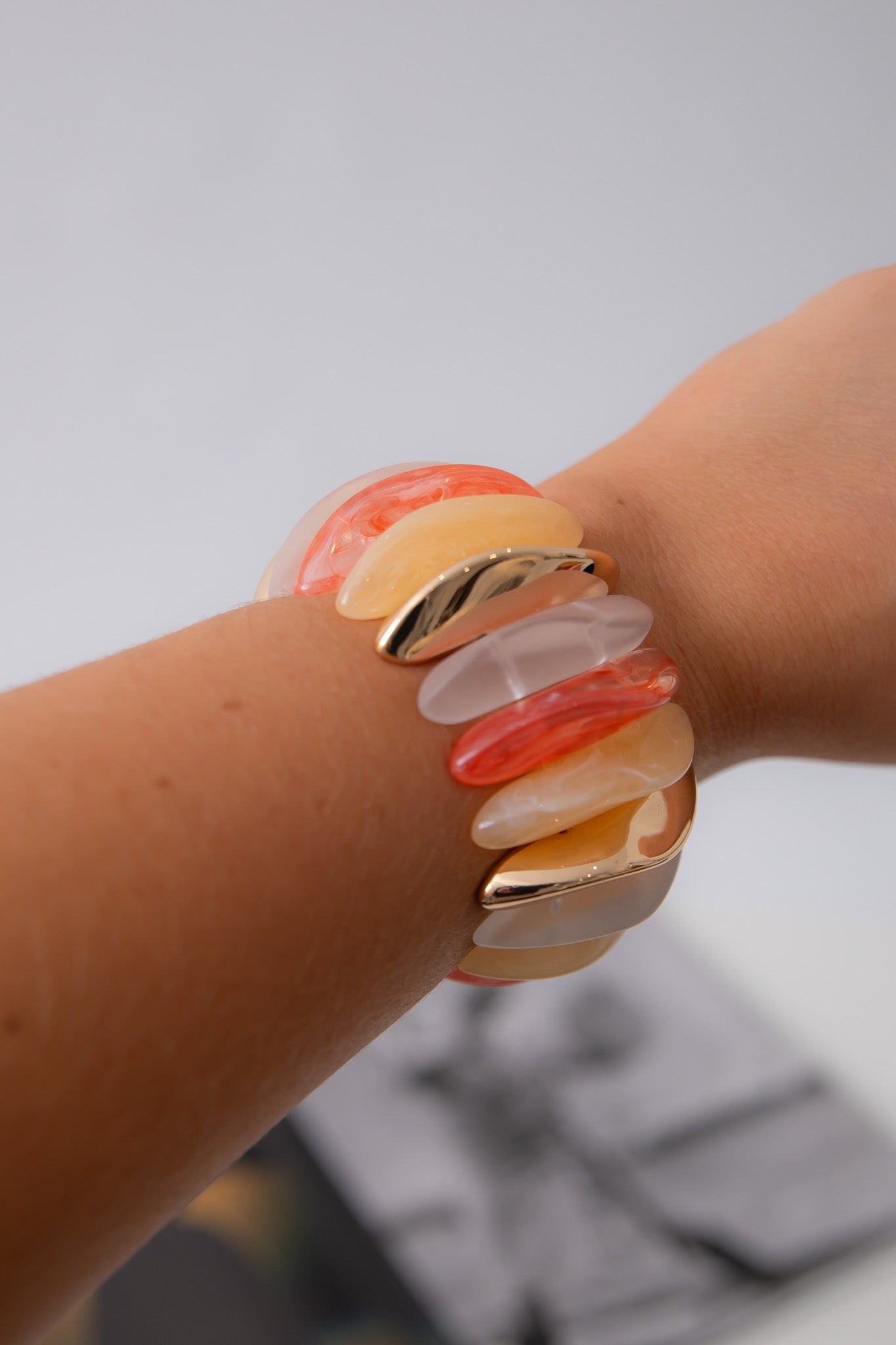 Orange Wide Stone Bracelet worn on wrist, featuring stretchy band with vibrant orange, peach, and gold-toned stones for summer statement jewelry.