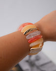 Orange Wide Stone Bracelet worn on wrist, featuring stretchy band with vibrant orange, peach, and gold-toned stones for summer statement jewelry.