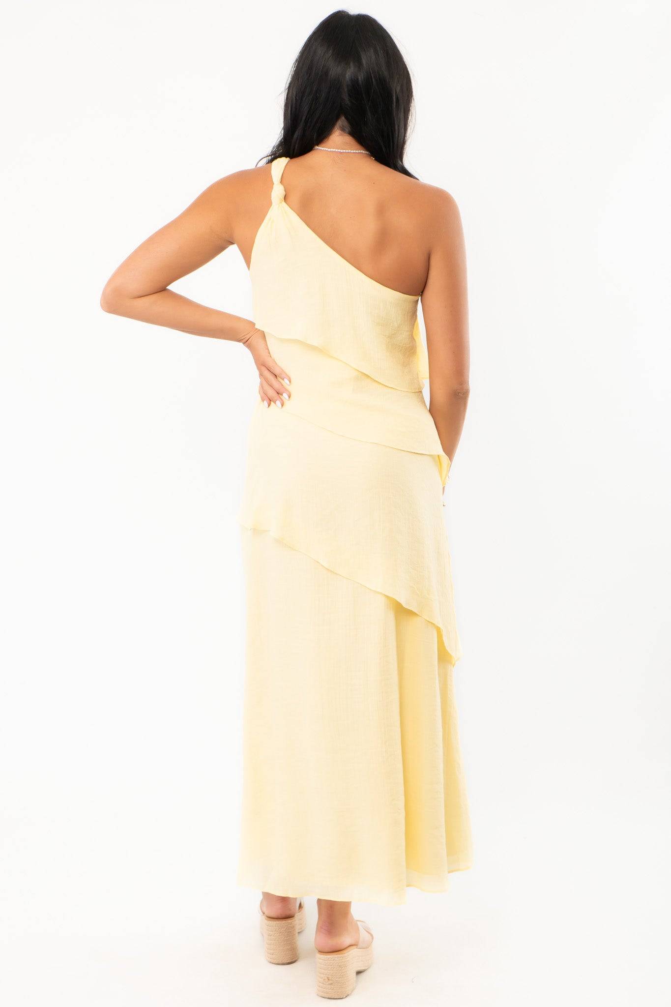 Back view of the Andie Yellow Layered One Shoulder Maxi Dress showcasing its flowing layered design and soft fabric texture.