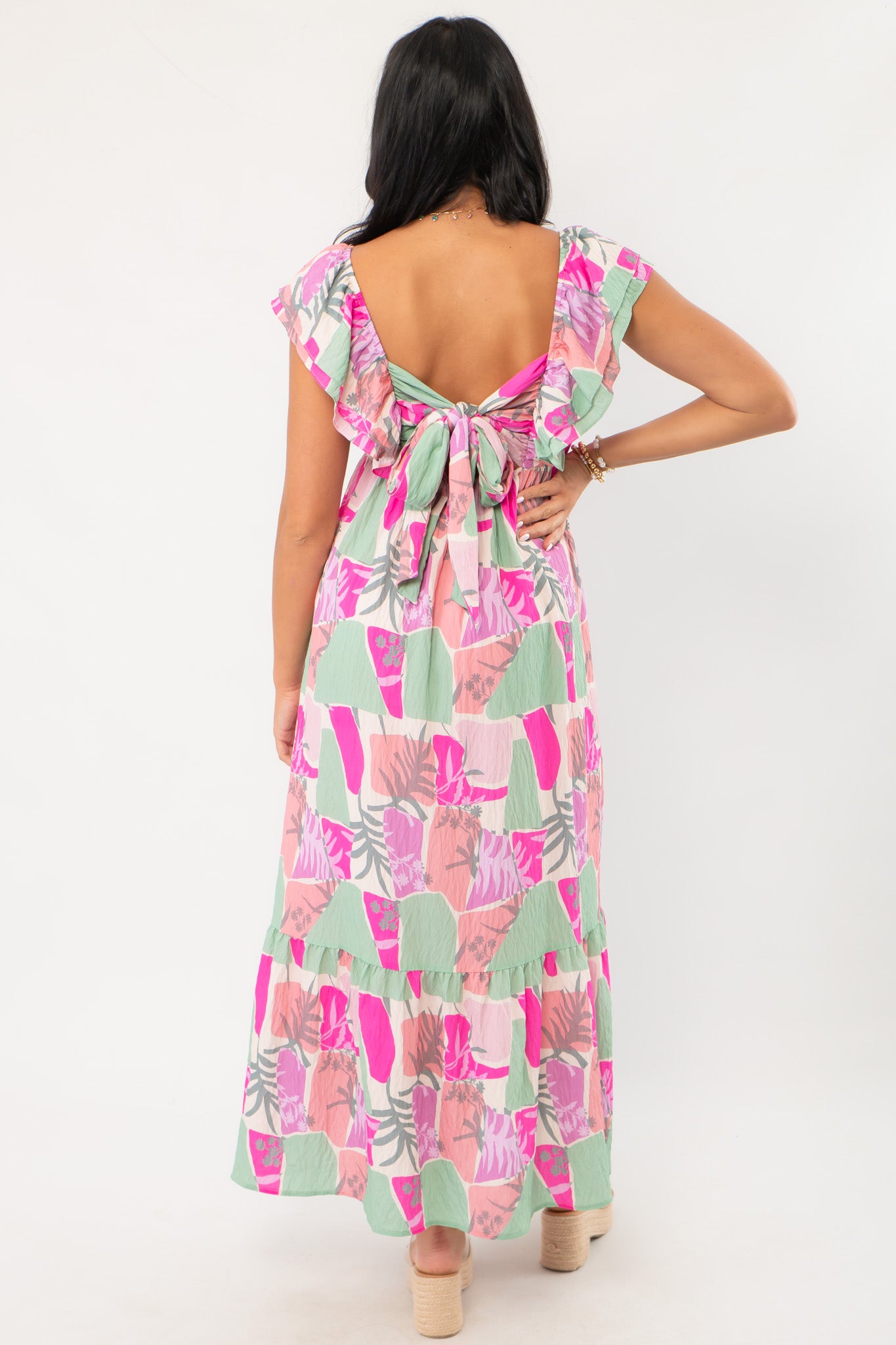 Back view of THML Pink Palm Ruffle Sleeve Maxi Dress showcasing tie-back detail and deep V-cut, ideal for garden parties or beach getaways.