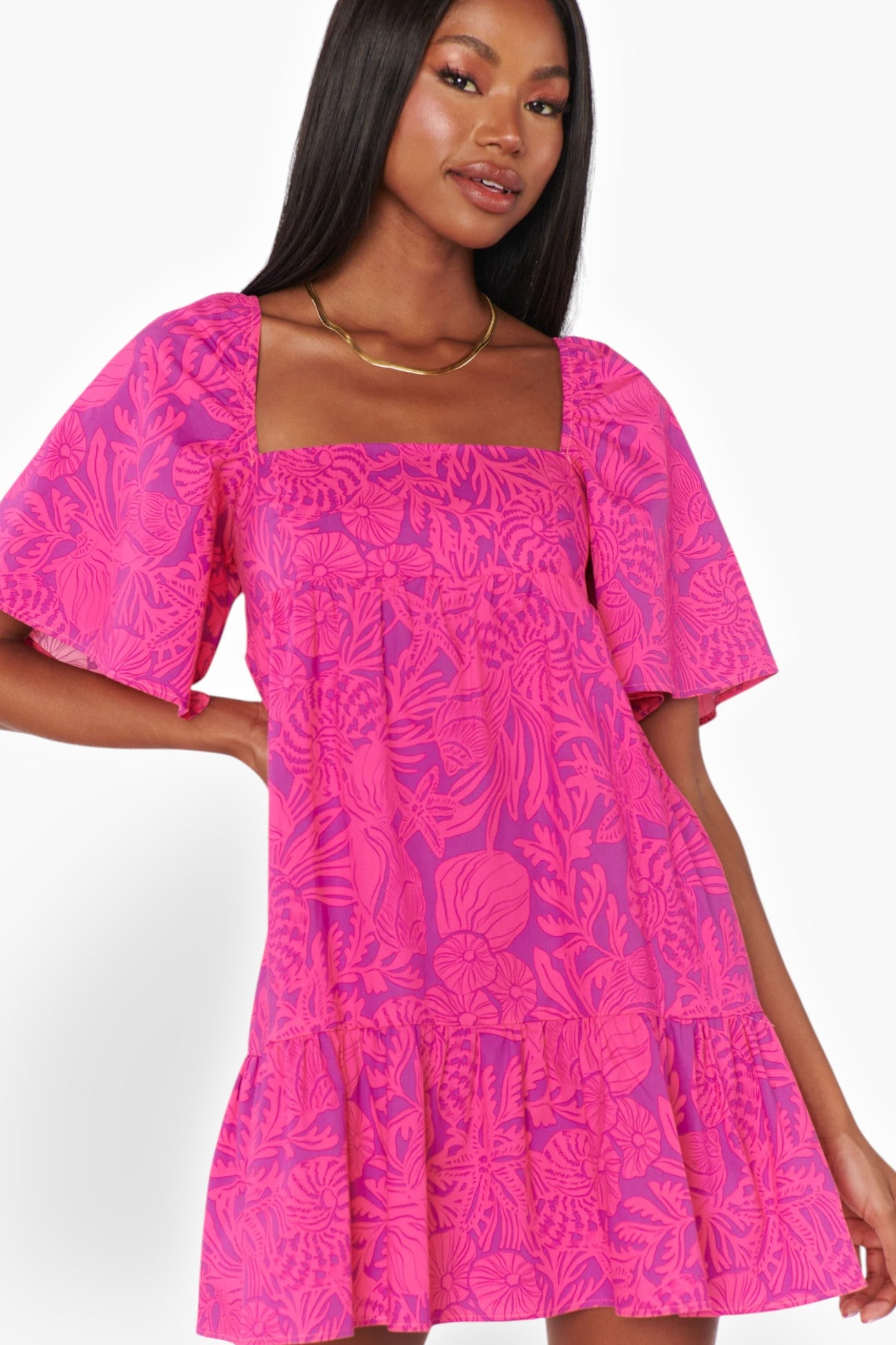 Front view of the Pink Shells Erin Mini Dress with a bold pink tropical print, square neckline, and flutter sleeves, perfect for warm-weather styling.