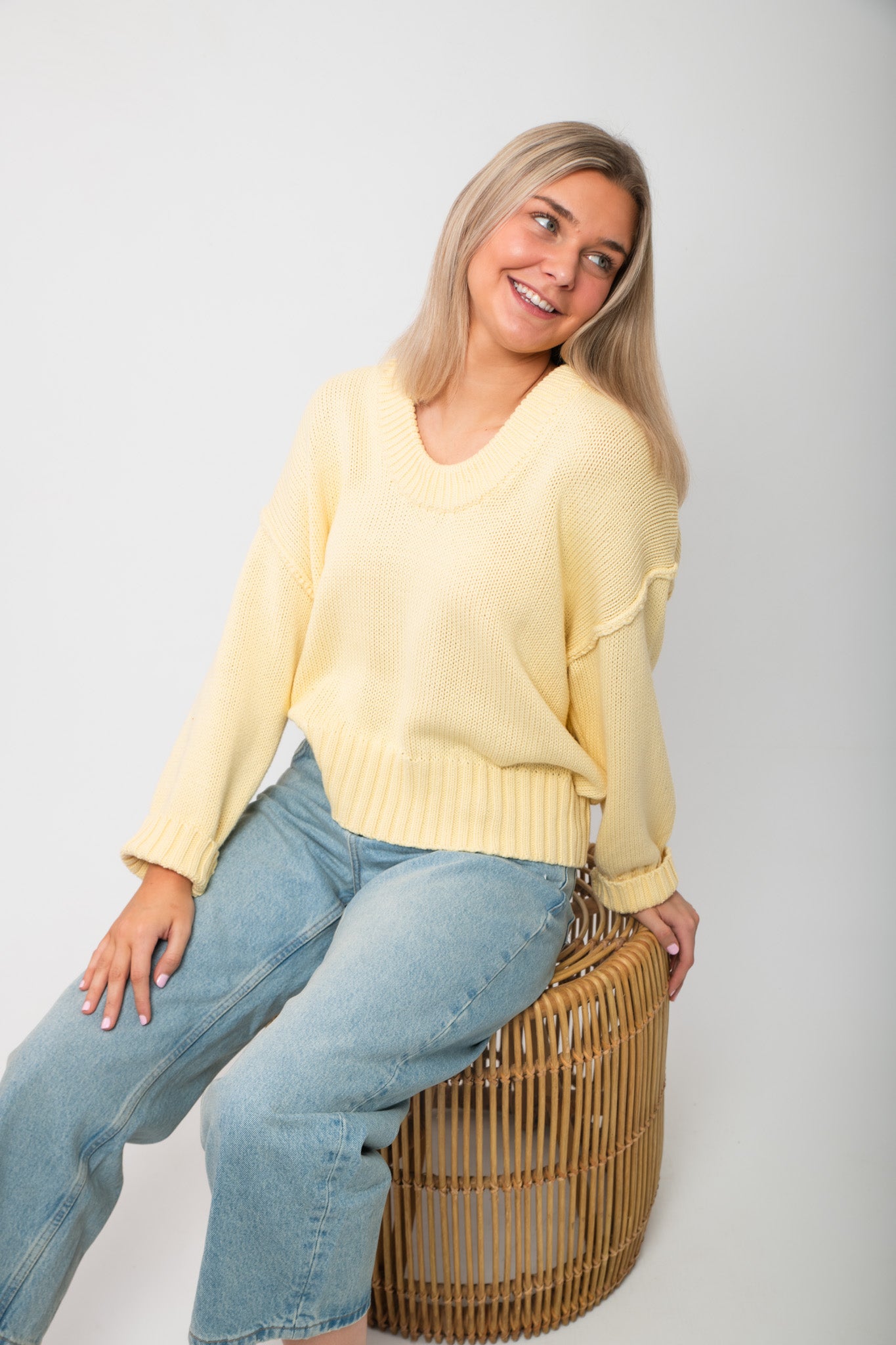 Casual seated pose in Lemon Sorbet Scoop Neck Sweater, showcasing its soft knit texture and cozy oversized silhouette for spring fashion.