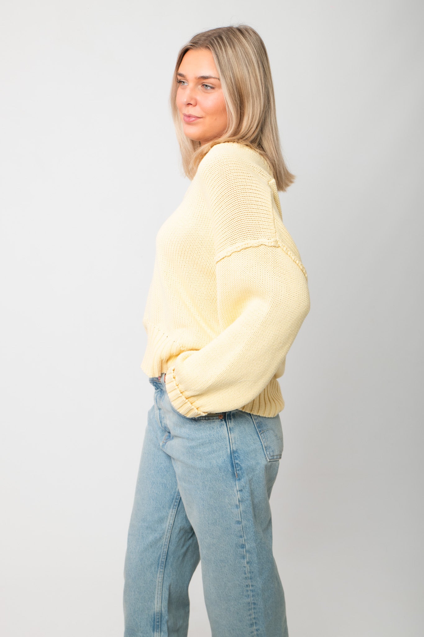 Side profile of Lemon Sorbet Scoop Neck Sweater – loose fit and dropped shoulders in a pastel yellow knit, styled with denim.