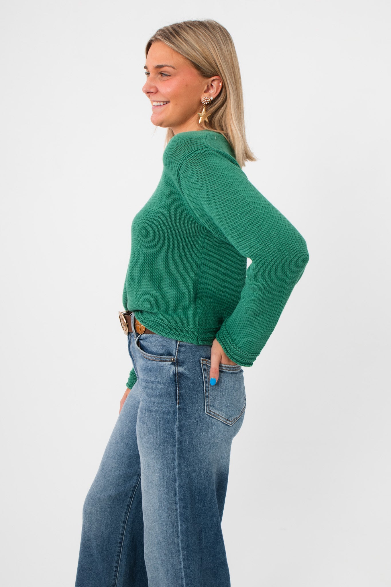 Side profile of Z Supply Botanical Green Emerson Sweater highlighting its airy open weave and soft texture, paired with wide-leg denim.