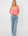 Model wearing Free People Conch Shell Pink Someone Like You Cami with flared jeans, showcasing a sleeveless, lace-trimmed camisole style.