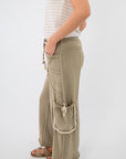Side view of Cactus Blossom Studded Wide Leg Pants – Smokey Sage featuring decorative stitching and a tasseled side pouch pocket.