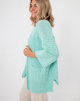 Side view of Mint Sorbet Chenille Slouch Cardigan highlighting its draped silhouette, front pockets, and ribbed knit texture.