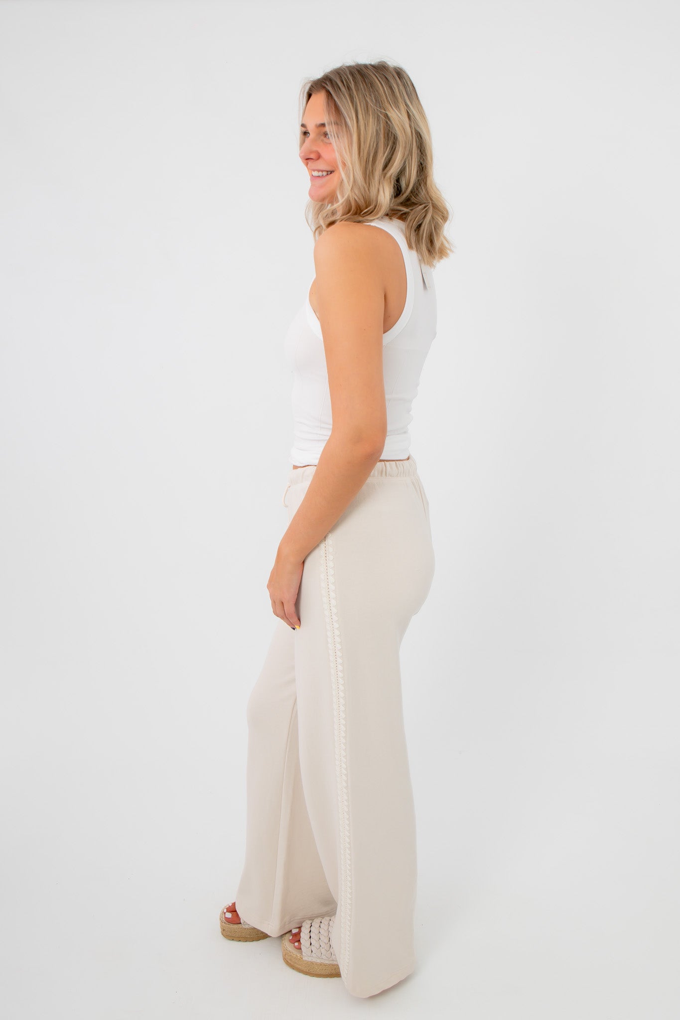 Side view of Free People Clean Ivory So Soft Seamless Modal Tank showing stretch fit and comfort, paired with wide-leg neutral pants.