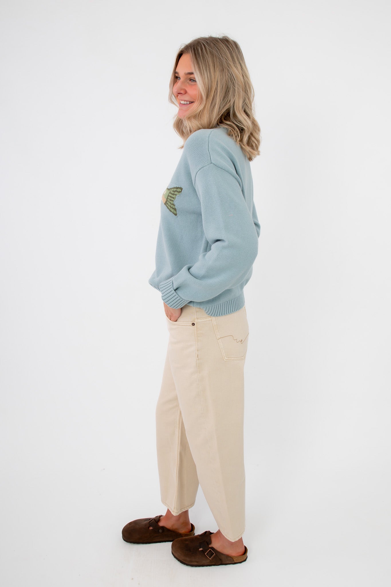 Side view of Catch of the Day Knit Fish Sweater highlighting relaxed fit and ribbed cuffs, paired with neutral wide-leg pants for a laid-back outfit.