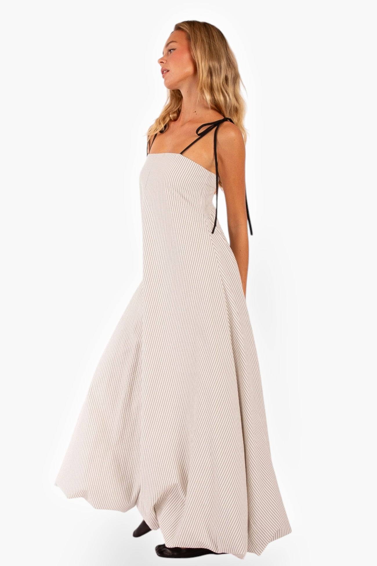 Elegant Shoreline Striped Maxi Dress with a voluminous bubble hem. The black tie straps add contrast to the soft striped fabric for a chic look.
